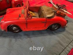 Vintage-style red tin toy car with skis and poles attached to the rear